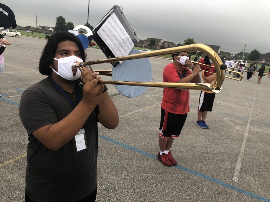 Senior Jose Ortega-Alvarez warms up his trombone in the south parking lot during an early morning practice. 