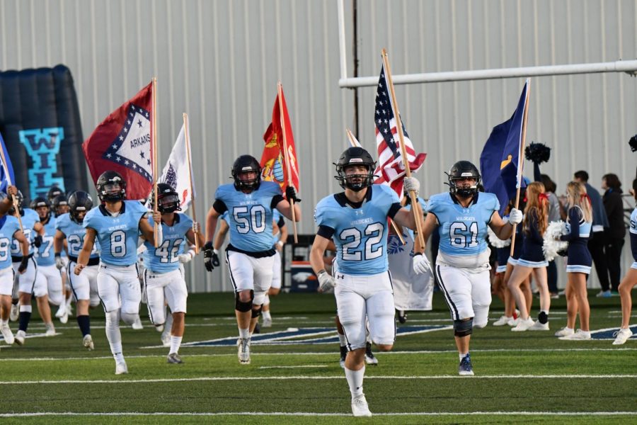 While+carrying+flags+that+represent+each+branch+of+the+armed+services%2C+senior+football+players+lead+the+team+on+to+the+field+wearing+their+new+Carolina+blue+jerseys.+