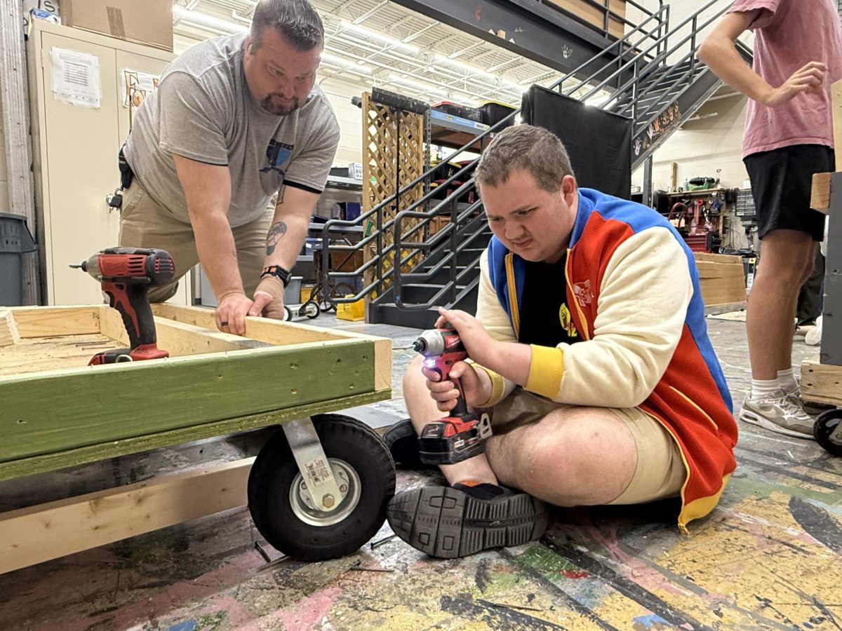 Theater students begin the prep work for adding a car onto a rolling cart that will be moved on and off stage during their fall performance. 
